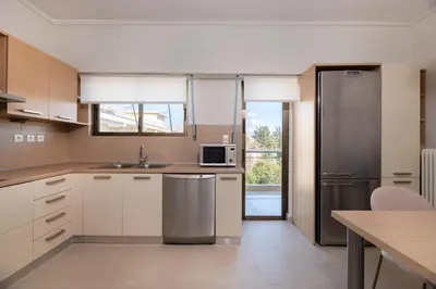 a kitchen with white cabinets and a stainless steel refrigerator at Comfort Living 3BR Apartment in Chalandri by UPSTREET in Athens