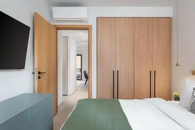 a bedroom with a bed and a wooden cabinet at Glyfada Signature Apartment in Athens