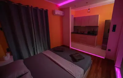 a room with a bed and a kitchen with pink lights at Smart Studio with Self Check-in in Athens