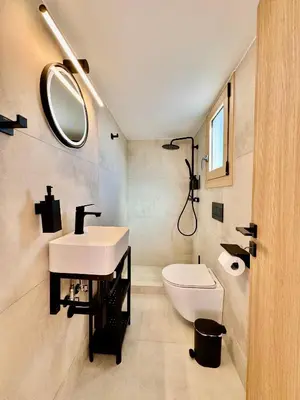 a bathroom with a sink and a toilet and a mirror at Rooftop Oasis - Design Studio with Acropolis View in Athens