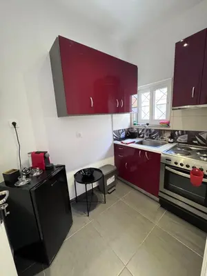 a kitchen with red cabinets and a sink and a table at Krezias Apartments K1 Acropolis View ! in Athens