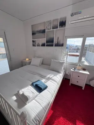 a bedroom with a white bed with a red carpet at Krezias Apartments K1 Acropolis View ! in Athens