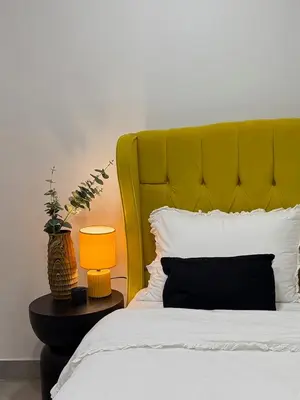 a bed with a yellow headboard and a table with a lamp at Beachfrond apartment in Voula in Athens