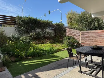 a patio with a table and chairs and a garden at Beachfrond apartment in Voula in Athens