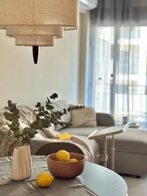 a living room with a table with a bowl of fruit at Brand New Apartment next to Varkiza Beach in Vari
