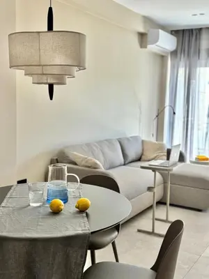 a living room with a table and a couch at Brand New Apartment next to Varkiza Beach in Vari