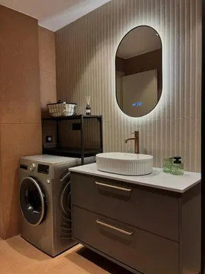 a bathroom with a washing machine and a sink at Brand New Apartment next to Varkiza Beach in Vari