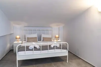 a white bed in a room with two lamps at Casa Anavyssos in Anavissos