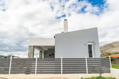 a white house with a fence in front of it at Casa Anavyssos in Anavissos