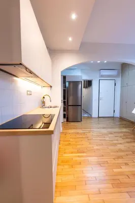 a kitchen with white cabinets and a wooden floor at HeKo Collection Athens Center 1 in Athens