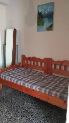 a wooden bed with a checkered blanket on it at Eleni's apartment in Piraeus