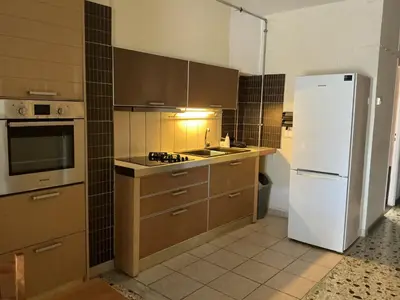 a kitchen with a white refrigerator and brown cabinets at Eleni's apartment in Piraeus