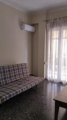 a couch sitting in a room with a window at Eleni's apartment in Piraeus