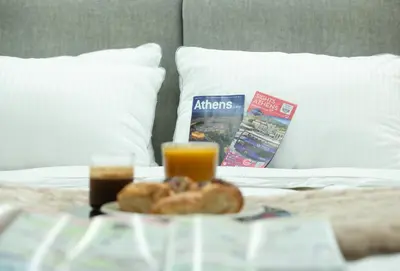 a tray of food on a bed with orange juice and donuts at Klitiou 7 Boutique Hotel in Athens