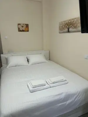 a white bed with two towels on top of it at Stylish City Apartment in Athens