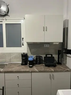 a kitchen with white cabinets and a counter top at Stylish City Apartment in Athens