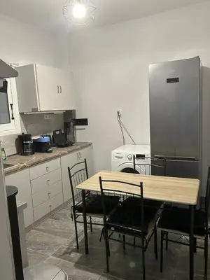 a kitchen with a table and chairs and a refrigerator at Stylish City Apartment in Athens