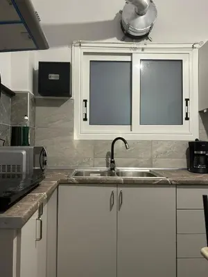 a kitchen with white cabinets and a sink at Stylish City Apartment in Athens