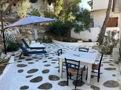 a patio with a table and chairs and an umbrella at Lagonisi Cottage - with spacious garden in Áyios Nikólaos