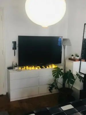 a flat screen tv sitting on a white dresser with candles at Roof top 5 steps from the beach in Athens