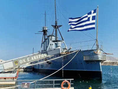 a large boat with an american flag sitting in the water at Roof top 5 steps from the beach in Athens