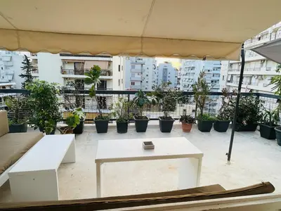 a patio with a white table and potted plants at Roof top 5 steps from the beach in Athens
