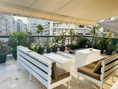 a patio with benches and plants on a roof at Roof top 5 steps from the beach in Athens