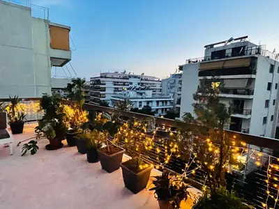 a group of potted plants on a balcony with buildings at Roof top 5 steps from the beach in Athens
