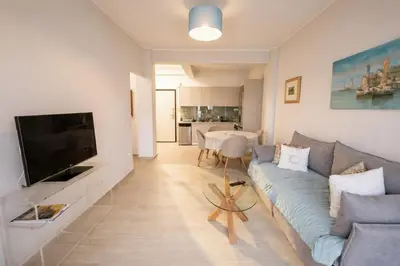 a living room with a blue couch and a television at The Varkiza Residence By the Sea in Vari