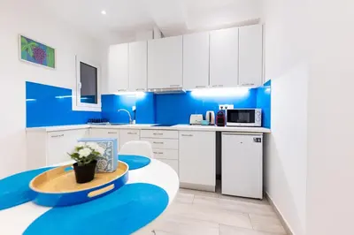 a kitchen with blue walls and white cabinets at HeKo Collection Athens 2 in Athens