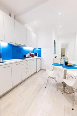a kitchen with white cabinets and a blue wall at HeKo Collection Athens 2 in Athens