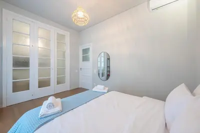 a white bedroom with a bed and a mirror at Zen Style, Exarchia in Athens