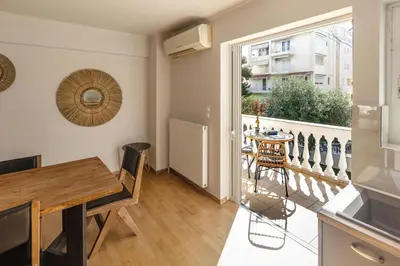 a kitchen and dining room with a table and a balcony at Dream House Voula in Athens