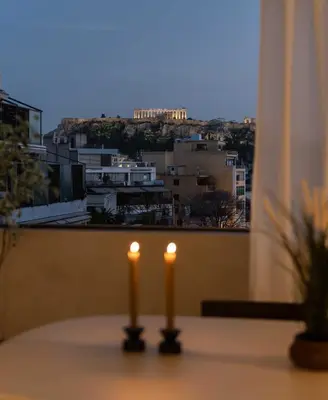 two candles sitting on a table in front of a window at ATELIER 57 , Stunning Acropolis View Monastiraki Apartment in Athens