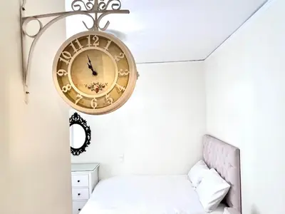 a large clock hanging on a wall above a bed at Central Studio Near Uni & Parks - Zografou by ΜΡS in Athens