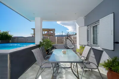 a patio with a table and chairs and a pool at Porto Blue Heaven in Porto Rafti