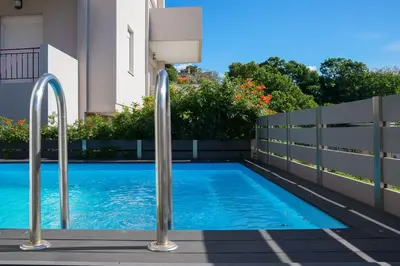 a swimming pool with metal rails next to a house at Porto Blue Heaven in Porto Rafti