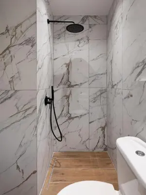 a bathroom with a shower with white marble walls at The White Apartment in Athens