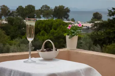 a table with a wine glass and a bowl on a balcony at Lagonisi Beach Villa in Lagonissi