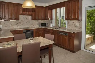 a kitchen with wooden cabinets and a table with chairs at Lagonisi Beach Villa in Lagonissi