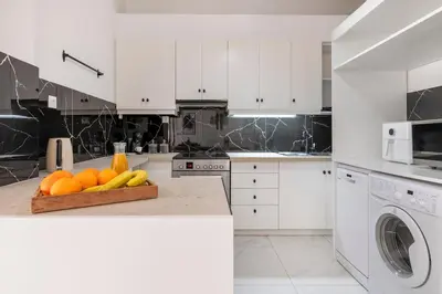 a white kitchen with a bowl of fruit on a counter at Sunlit 3BDR Family APT, Near Sea & City Center! in Athens