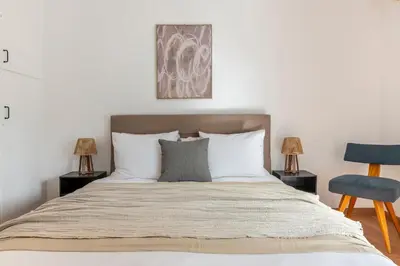 a bedroom with a bed with two lamps and a chair at Sunlit 3BDR Family APT, Near Sea & City Center! in Athens
