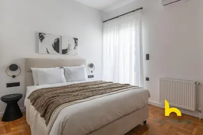a white bedroom with a large bed and a window at Sunlit Balcony Family APT Whirpool & Netflix in Athens