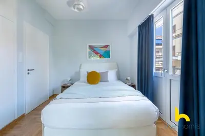a white bed in a room with a window at Retro Radiance Artistic Haven Near Acropolis in Athens