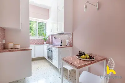 a kitchen with white cabinets and a table with a bowl of fruit at Retro Radiance Artistic Haven Near Acropolis in Athens
