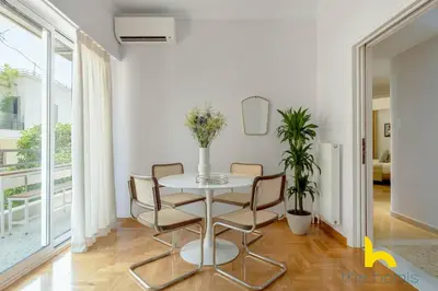 a white dining room with a table and chairs at Retro Radiance Artistic Haven Near Acropolis in Athens