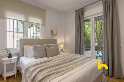 a bedroom with a large bed with a large window at Sun Splashed Sanctum w Green Patio, Acropolis in Athens