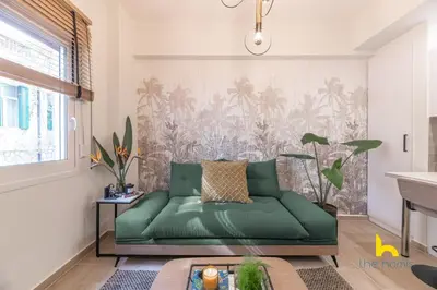 a green couch in a living room with a wall at The Urban Jungle Escape Corner APT Near Acropolis in Athens