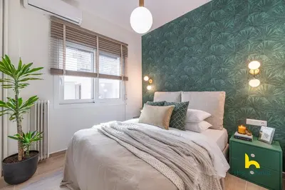 a bedroom with a bed with a green accent wall at The Urban Jungle Escape Corner APT Near Acropolis in Athens