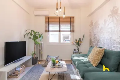 a living room with a green couch and a tv at The Urban Jungle Escape Corner APT Near Acropolis in Athens